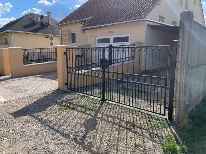 Kétszárnyú nyíló kapu és kerítés egy családi ház előtt